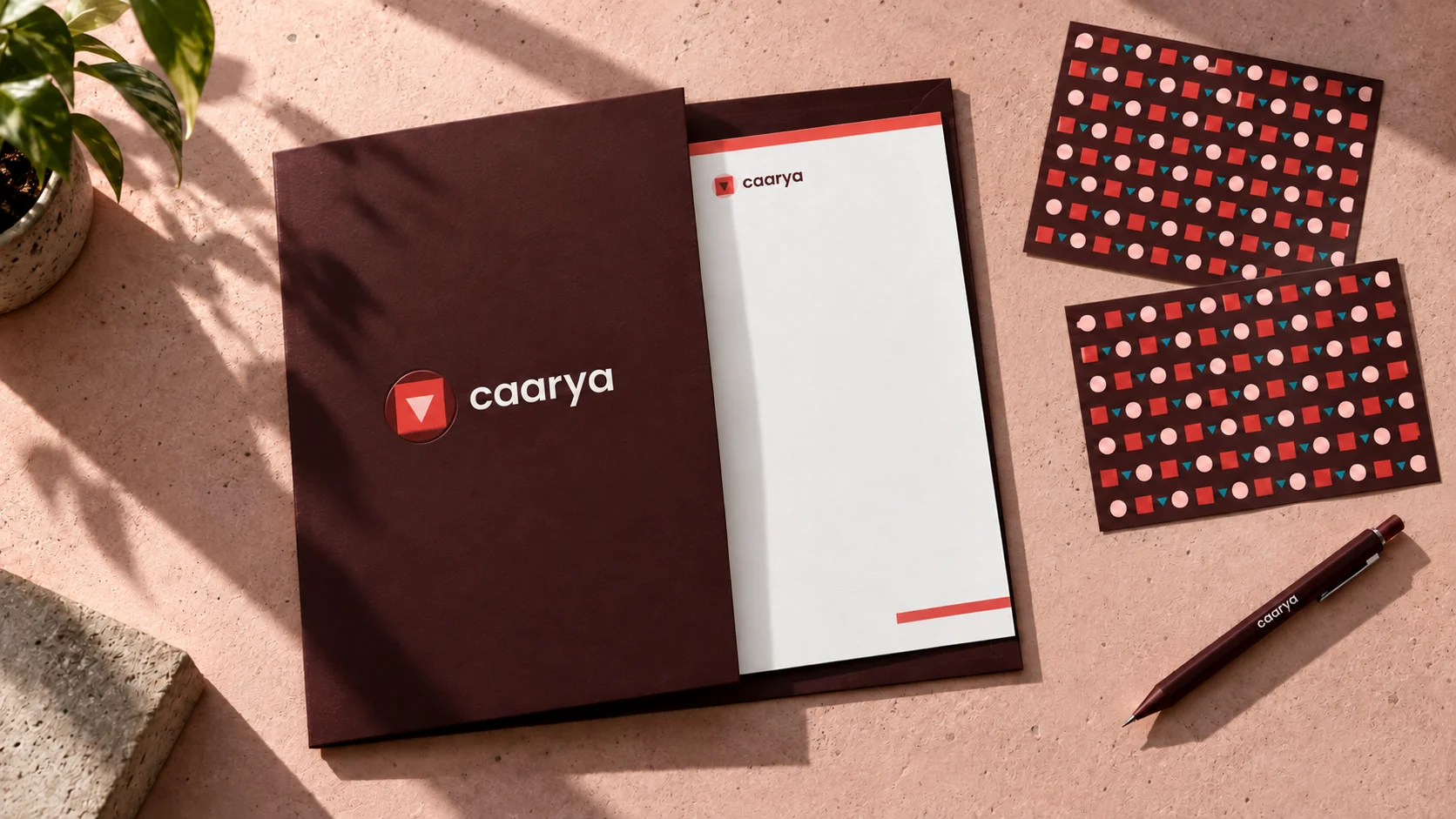 Caarya identity mockup across a burgundy folder, stationery and geometric pattern cards.